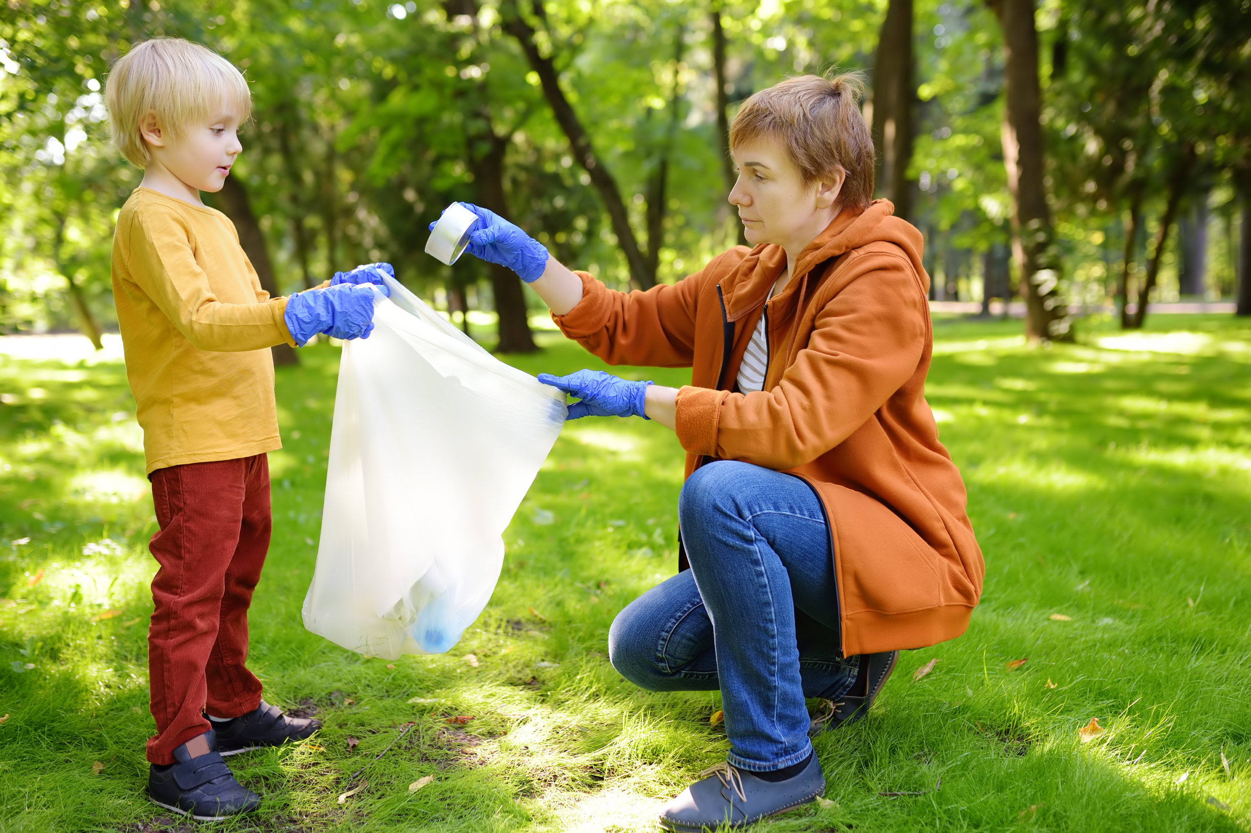Lapsi ja aikuinen keräävät puistosta roskia